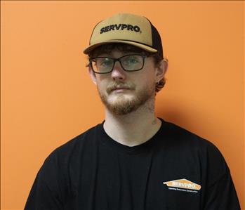 A man in a black shirt standing in front of an orange background