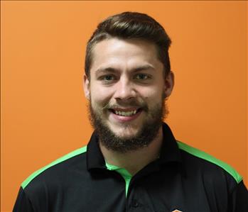 A woman in a black shirt standing in front of an orange background