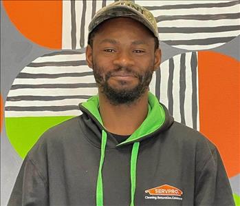 malcom (man) standing in front of green and orange mural background 