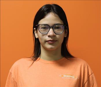 A woman in an orange shirt standing in front of an orange background