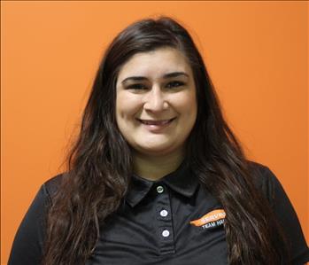 A woman in a black shirt standing in front of an orange background